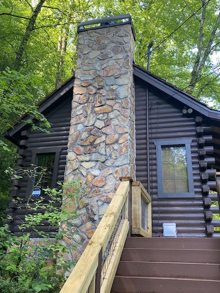 Stained cabin exterior with stone chimney